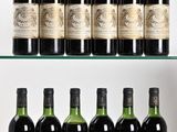 Plusieurs bouteilles de vin sont posées sur une étagère en verre devant un mur blanc.
