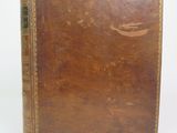 an old book with a brown cover sitting on top of a white surface