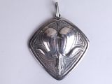 a silver pendant with a bird on it on a white surface