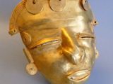 gold mask on a blue background with a metal chain around it