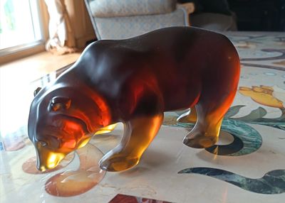 un ours en verre posé sur une table à motifs floraux