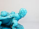 une figurine bleue représentant un garçon tenant un bébé dans ses bras