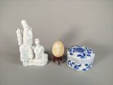 une figurine blanche posée à côté d'une boîte bleue et blanche et d'un œuf