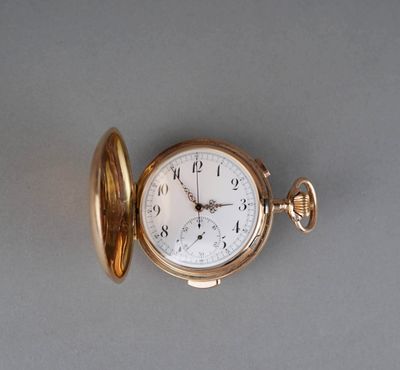a gold pocket watch sitting on a gray surface