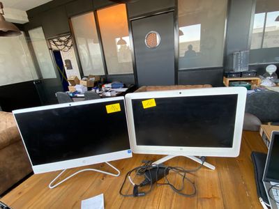 two computer monitors sitting on a table in a living room