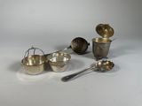 un assortiment d'ustensiles en argent, comprenant notamment des cuillères, des verres doseurs et des cuillères à mesurer