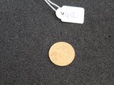 a gold coin on the ground next to a price tag