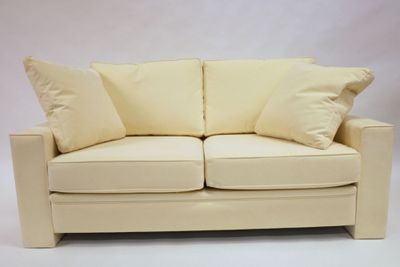 cream colored couch with pillows on it against a white background