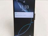 a close up of the back of a black phone on a white surface