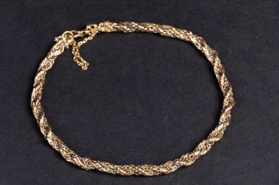 gros plan d'un bracelet en chaîne en or sur une surface noire