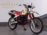 a red and white motorcycle parked in front of the pinnacle collection sign
