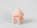 une petite figurine rose représentant un chien, posée sur une surface blanche