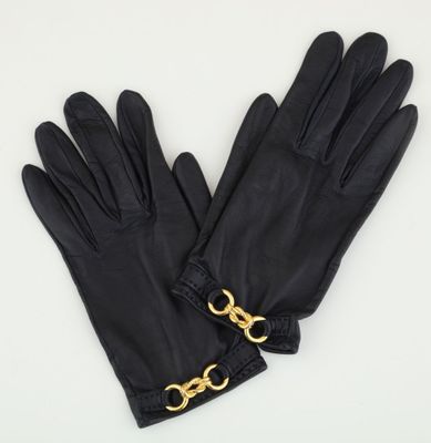 a pair of black leather gloves with gold chains on them