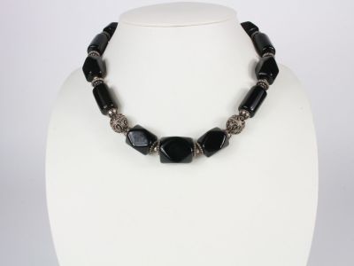 a black and silver necklace on a white mannequin
