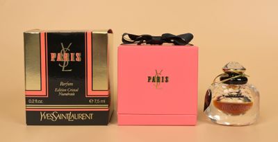 un flacon de parfum et un coffret de parfum posés sur une table, à côté d'une boîte rose