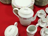 many plates and cups on a table with a red table cloth