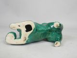 a green and white figurine of a dog laying on the ground