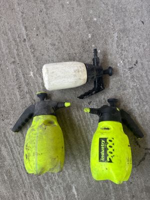 Trois pulvérisateurs manuels: deux jaunes et un blanc