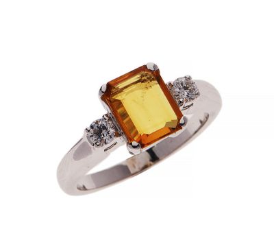 a close up of a ring with an orange stone and diamonds