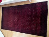 a red rug on the floor next to a white shelf