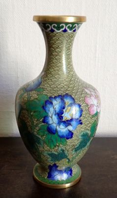 a green vase with blue flowers on it on a table