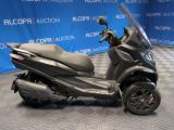a black scooter parked in front of a blue backdrop