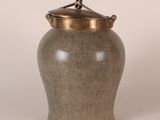 une image représentant un vase gris avec un couvercle doré sur fond blanc