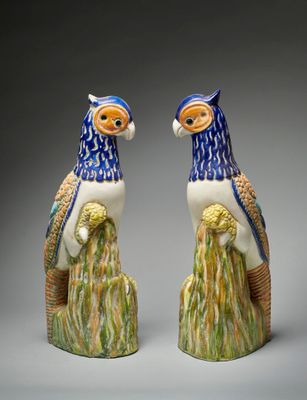 une paire de perroquets en céramique bleue et blanche, perchés sur une souche d'arbre