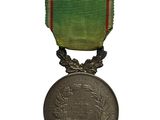 an old medal with a green ribbon and a red ribbon around it