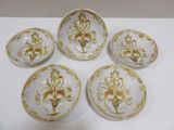 quatre assiettes ornées de motifs dorés et blancs, posées sur une table