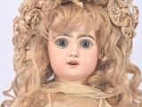 a doll with blonde hair wearing a gold dress and a hat
