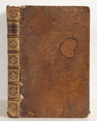 an old book sitting on top of a white table next to a white wall