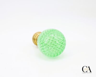un gros plan d'un bouton en verre vert sur fond blanc
