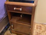 a small nightstand with a phone on it next to a bed