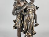 a bronze statue of two women holding flowers on a pedestal