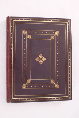 un livre marron aux bords dorés sur une couverture blanche