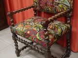a chair with a colorful upholstered seat and a red curtain