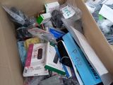 a cardboard box full of electronic items on a bed