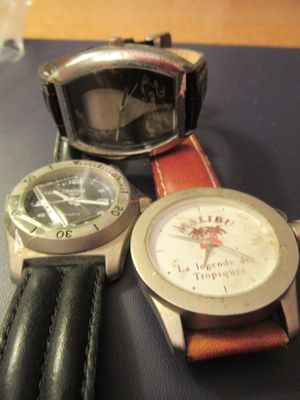 Plusieurs montres sont posées sur une table, à côté d'un verre d'eau