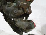 une main tenant une statue représentant une tête de lion