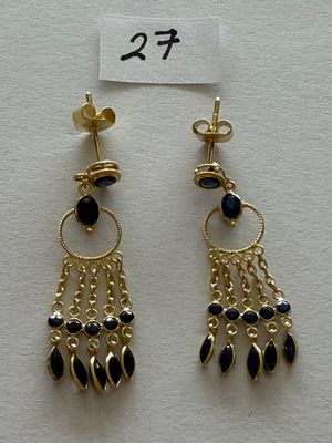 a pair of black and gold earrings on a white surface
