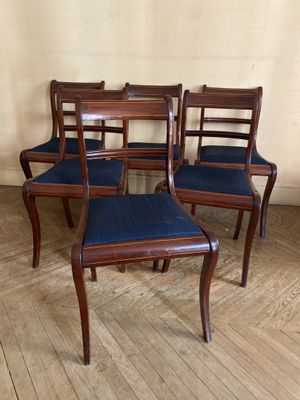 quatre chaises en bois avec des assises rembourrées bleues dans une pièce