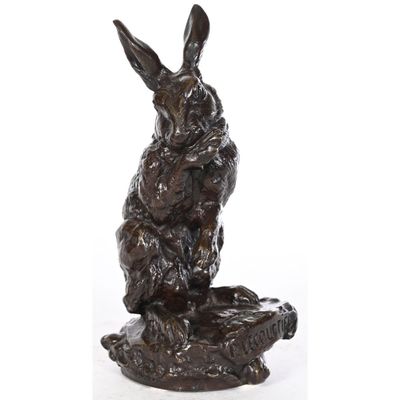 une statue en bronze représentant un lapin assis sur un rocher