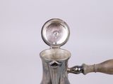 an antique silver coffee pot with a wooden handle on a white surface