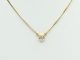 a gold necklace with a diamond on a mannequin neck