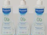 trois flacons de gel hydroalcoolique Mustela posés sur une table