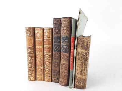 several old books are stacked on top of each other on a white surface