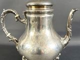 une théière ancienne en argent avec couvercle, posée sur un socle