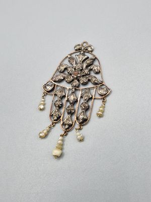 un gros plan sur une broche en or et perles