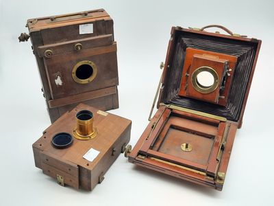 trois appareils photo anciens sont posés les uns à côté des autres sur une surface blanche